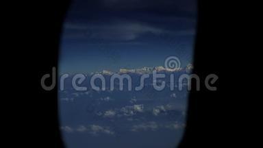 在雪山和云层上形成一个飞机窗口的视图。